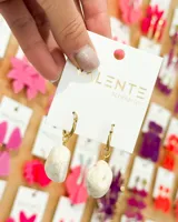 Aros colgantes con aro dorado y dije de piedra blanca con vetas marrones.