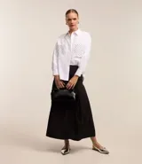 Falda midi evasé negra, confeccionada en tricolina, con pliegues y sin estampado.