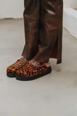 Mules con estampado animal print, con hebilla plateada y suela negra.