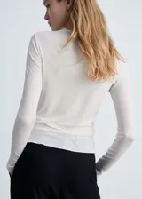 Camiseta blanca de tejido de punto fino con cuello redondo y mangas largas.