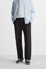 Pantalón de vestir negro de corte recto, con cintura elástica, pliegues frontales, bolsillos laterales y traseros.