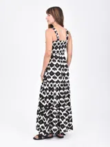 Vestido largo estampado en blanco y negro con detalles en marrón. El diseño presenta un estampado tipo ikat o animal print abstracto. El vestido tiene tirantes anchos y un corte con vuelo en la falda a la altura de la rodilla.