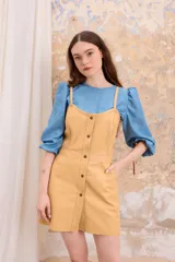 Vestido corto color beige de cuero sintético, estilo jumper con breteles finos y botones frontales.