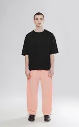 Pantalón de corte sastrero color salmón, de tela suede suave y holgada, con bolsillos laterales, cintura trasera elástica ajustable y cierre frontal con botón.