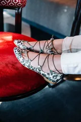 Bailarinas con estampado animal print en tonos verde y marrón, con base de napa naranja y cordones finos con borlas.