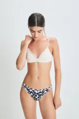 Conjunto de ropa interior color crema, compuesto por un corpiño de encaje con breteles finos y una bombacha tipo colaless con detalle de encaje en la cintura.