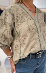 Camisa color verde oliva con bordado floral, de manga larga con puños elásticos y cierre frontal con botones.