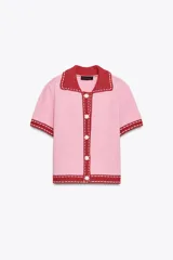Chaqueta de punto rosa con cuello solapa y manga corta. Cierre frontal con botones y ribete rojo en cuello, mangas y bajo.