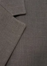 Blazer marrón con solapas de muesca, cierre frontal con un botón, bolsillos con solapa y corte entallado.