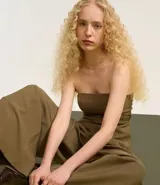Blusa sin breteles color verde militar, confeccionada en crepé, con cierre de cremallera en la espalda y cinturón elástico con hebilla negra.
