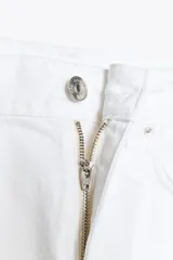 Pantalón de jean blanco, de tiro medio y corte wide leg, con cinco bolsillos y costuras laterales marcadas.