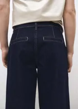 Pantalón de jean azul oscuro, corte wideleg, tiro medio, con pinzas delanteras, bolsillos laterales y traseros.
