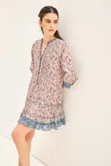 Vestido corto de corte amplio con volados en el ruedo y mangas 3/4 abullonadas. Presenta combinación de estampados florales en voile de algodón. Tiene cuello mao y cierre frontal con botones.