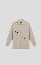 Camisa beige de manga larga, estilo técnico con múltiples bolsillos delanteros y un bolsillo en la parte inferior de la espalda, botones en la cartera y mangas, calce oversize, confeccionada en textil ligero suave al tacto.