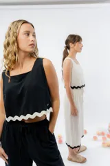 Top de lino color crudo, con escote cuadrado y detalle de guarda ondulada negra en el ruedo.