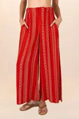 Pantalón de corte recto color rojo con estampado de cadenas doradas, pretina elástica, cierre y broche al frente, pinzas y bolsillos laterales.