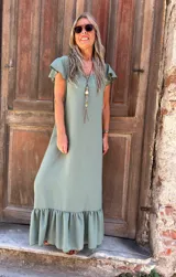 Vestido largo color verde salvia, de corte recto y holgado, con escote en V y mangas cortas con volados. El ruedo termina con un volante fruncido.