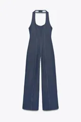 Mono largo de denim azul, con cuello halter y escote redondo. Detalle de pespuntes a contraste. Espalda descubierta. Pierna ancha. Cierre en cuello.