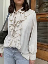 Camisa color crema de lana tejida con cuello camisero y volados frontales.