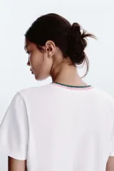 Camiseta blanca de algodón con cuello redondo y detalle de tricot a contraste en azul marino. Estampado frontal con texto "Estate sulla Costiera Amalfitana" en azul marino.