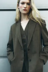 Blazer marrón de Zara Woman Collection, con cuello solapa y manga larga. Tiene bolsillos de vivo en el delantero y cierre frontal cruzado con botón.