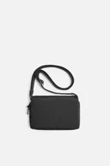Bandolera negra de nylon con solapa y cierre magnético. Tiene correa ajustable con mosquetón y bolsillo interior.
