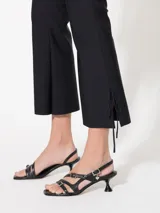 Pantalón negro con cintura rebatida y cierre lateral. Diseño entallado con pinzas delanteras y traseras, corte flare y tajo en el ruedo con moño.