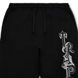 Conjunto deportivo negro de buzo con capucha y pantalón de jogging, ambos con logo "Trapstar" en letras góticas blancas con contorno plateado. El buzo tiene cierre frontal y bolsillo tipo canguro. El pantalón tiene cordón ajustable en la cintura y tobillos ajustables.