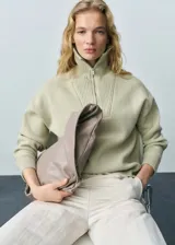 Sweater verde claro de punto medio con cuello alto y cierre de cremallera.