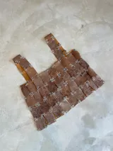 Top sin mangas de diseño calado, confeccionado con tiras de material sintético marrón con estampado de serpiente y ojales metálicos plateados que se entrelazan.