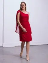 Vestido de fiesta azul marino de seda fría, corte a la rodilla, con un hombro descubierto y aplique de lentejuelas plateadas en el bretel. Incluye una capa de gasa transparente que se sujeta al hombro.