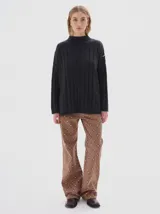 Buzo tejido color blanco, con cuello subido tipo polera, diseño oversized y largo con pequeños cortes laterales.