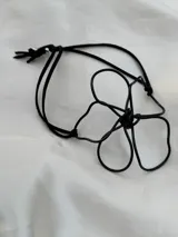 Pulsera con dije de flor de alambre negro y cordón de gamuza negro ajustable.