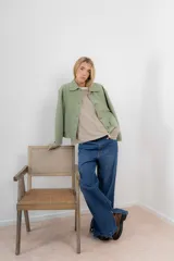 Chaqueta corta tipo blazer color marrón, confeccionada en tela de lana afieltrada. Tiene cuello camisero, silueta cuadrada, cierre frontal con botones y bolsillos delanteros.