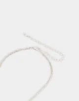 Collar multicadena plateado con dije de corazón calado y dije de cuentas cilíndricas.