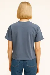 Remera color verde claro de algodón con cuello redondo y mangas cortas. Estampado frontal con dibujo de una pierna estilizada con zapato de tacón y corazones.