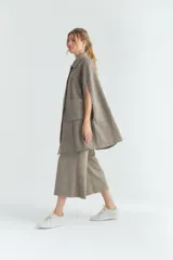 Capa larga color marrón claro con textura tipo tweed, con botones en la parte delantera y bolsillos laterales.