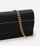 Cartera transversal pequeña de poliuretano negro con detalles en blanco y asa de cadena dorada.