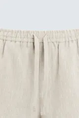 Pantalón de lino color marrón oscuro, de corte recto y relaxed fit. Tiene cintura elástica ajustable con cordón, bolsillos frontales y traseros de parche.