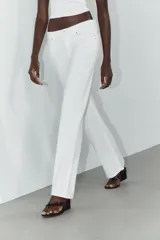 Jeans de mezclilla azul oscuro con efecto lavado, tiro bajo y pierna ancha extra larga. Modelo de cinco bolsillos con cierre frontal de cremallera y botón metálico.