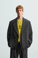 Blazer negro de corte relajado con cuello de solapa de muesca desmontable, manga larga, bolsillos frontales ocultos y cierre frontal con botones.