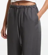 Pantalón fluido gris con cintura elástica y lazo ajustable.