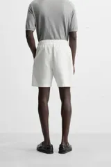 Bermuda negra regular fit confeccionada en tejido de algodón con estructura. Cintura elástica ajustable con cordón, bolsillos laterales y bolsillo trasero de vivo.