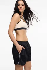 Short deportivo color bordó de tela satinada con cintura elastizada, bolsillos laterales y franja lateral blanca.