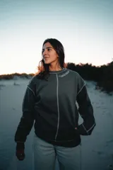 Buzo gris con costuras blancas a la vista, cuello redondo y logo estampado en el pecho.