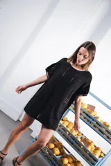 Vestido corto negro con patrón calado cuadrado, cuello redondo y mangas cortas con terminaciones a contratono en blanco.