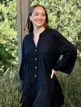 Vestido corto negro de lino, con escote en V, botones frontales y mangas largas acampanadas con volados.