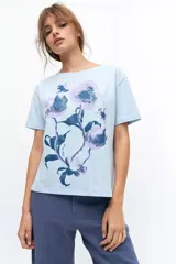 Remera lila de algodón con estampado de flores en tonos naranja y rosa.