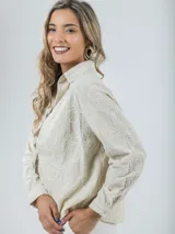 Blusa color crudo con bordados florales, cuello camisero y mangas largas.
