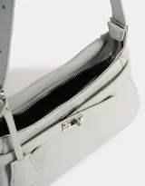Bandolera de cuerina color gris claro, con correa de hombro ajustable, cinturón frontal decorativo y charm lateral con forma de mariquita.